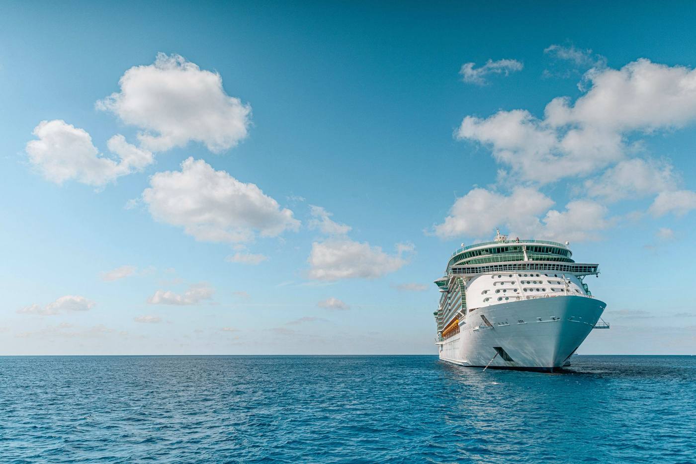 A white cruise ship at sea under a bright blue sky